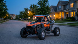 Smiling young boy driving an orange Kids Rider UTV.
