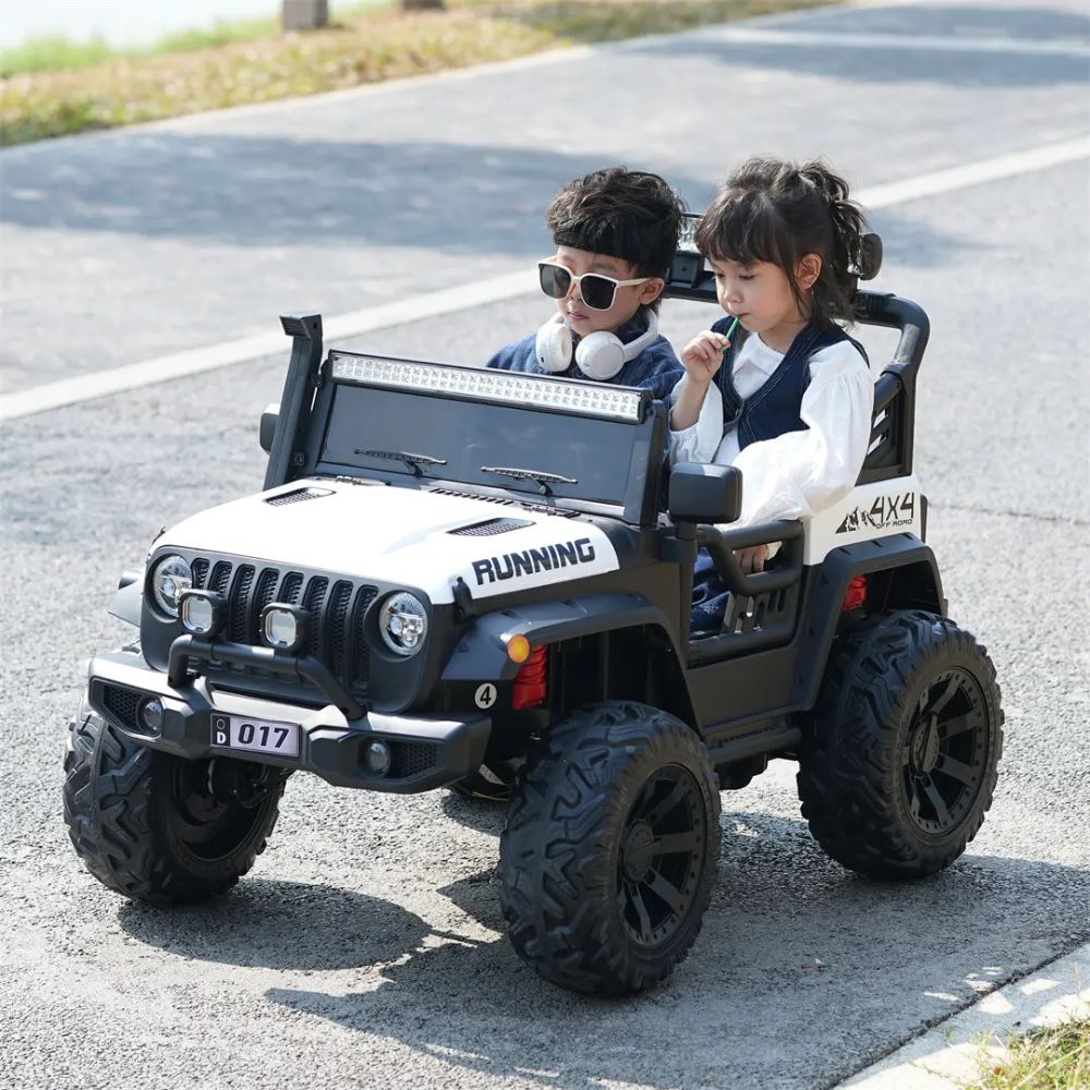 Two young children riding together in a white Kids Rider 4x4 off-road jeep.