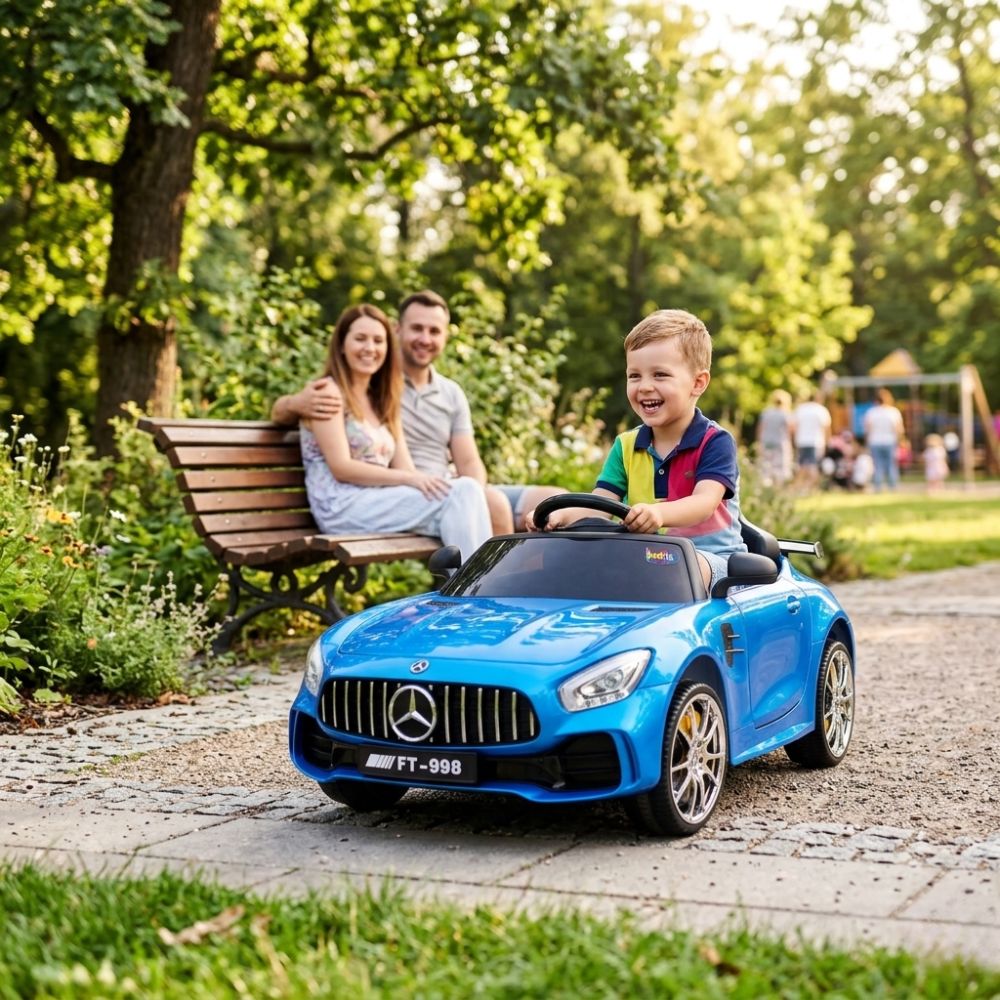 Child in a blue toy car with parents sitting on a bench in a park.